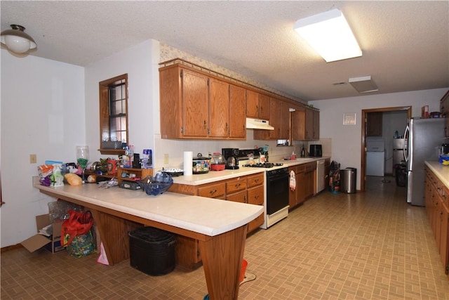 kitchen featuring stainless steel appliances, a kitchen breakfast bar, kitchen peninsula, and a textured ceiling