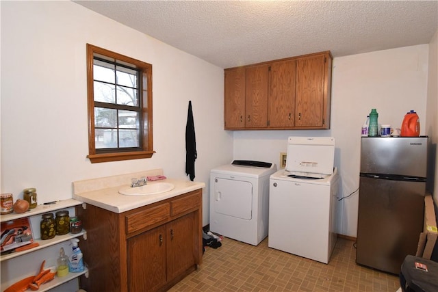 laundry area featuring sink, a textured ceiling, and washer and clothes dryer