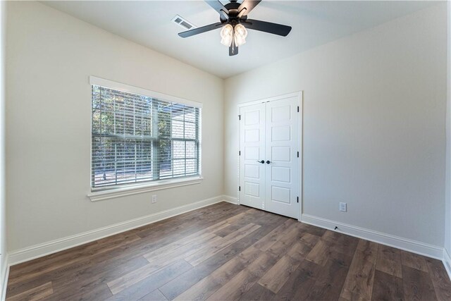 unfurnished bedroom featuring dark hardwood / wood-style flooring, ceiling fan, and a closet