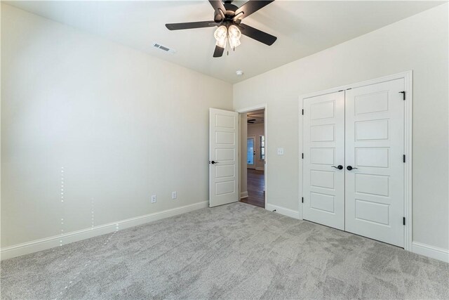 unfurnished bedroom featuring light colored carpet, a closet, and ceiling fan