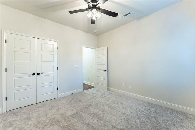 unfurnished bedroom with light carpet, ceiling fan, and a closet