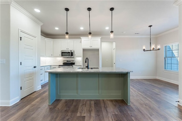 kitchen with decorative light fixtures, an island with sink, stainless steel appliances, light stone countertops, and white cabinets