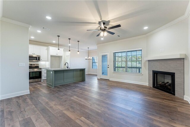 kitchen featuring sink, appliances with stainless steel finishes, a kitchen island with sink, white cabinets, and decorative light fixtures