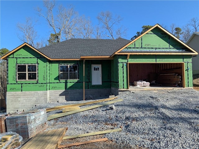 property under construction with gravel driveway, an attached garage, and a shingled roof