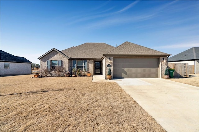 ranch-style house featuring a front yard, an attached garage, a shingled roof, concrete driveway, and brick siding