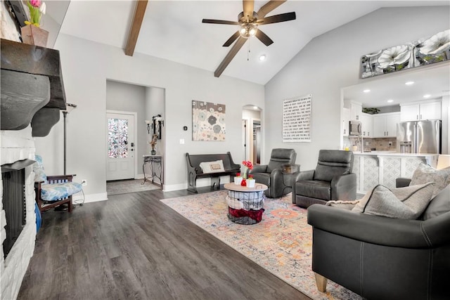 living room with ceiling fan, dark hardwood / wood-style floors, lofted ceiling with beams, and a stone fireplace