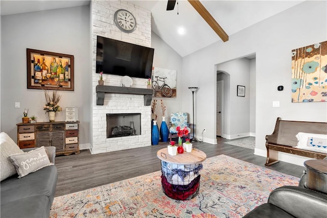 living room with a brick fireplace, lofted ceiling with beams, dark hardwood / wood-style floors, and ceiling fan