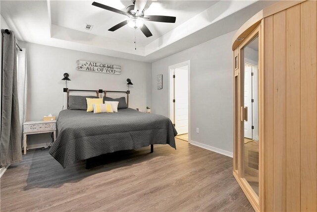 bedroom featuring wood-type flooring, a raised ceiling, and ceiling fan