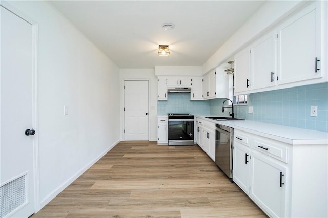 kitchen featuring sink, light wood-type flooring, white cabinets, stainless steel appliances, and backsplash