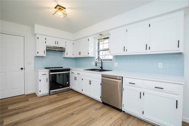 kitchen with sink, stainless steel appliances, white cabinets, decorative backsplash, and light wood-type flooring