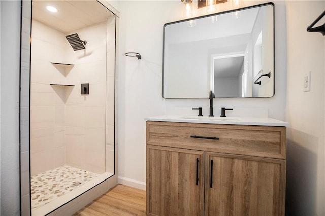 bathroom featuring hardwood / wood-style flooring, tiled shower, and vanity