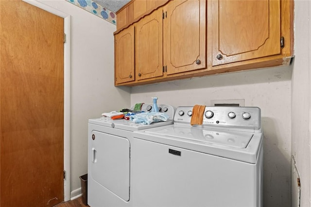 clothes washing area featuring cabinets and washer and dryer