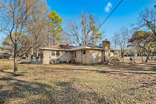 rear view of house with central AC unit and a lawn