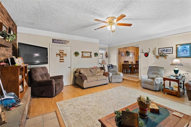 living room featuring ceiling fan, a textured ceiling, and light hardwood / wood-style flooring