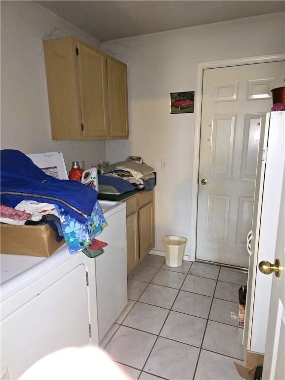 clothes washing area with light tile patterned floors, washer and clothes dryer, and cabinets