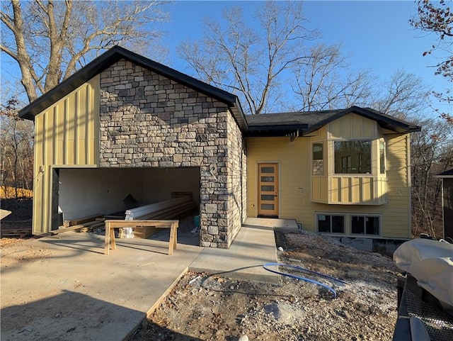 view of front facade featuring stone siding, concrete driveway, and an attached garage