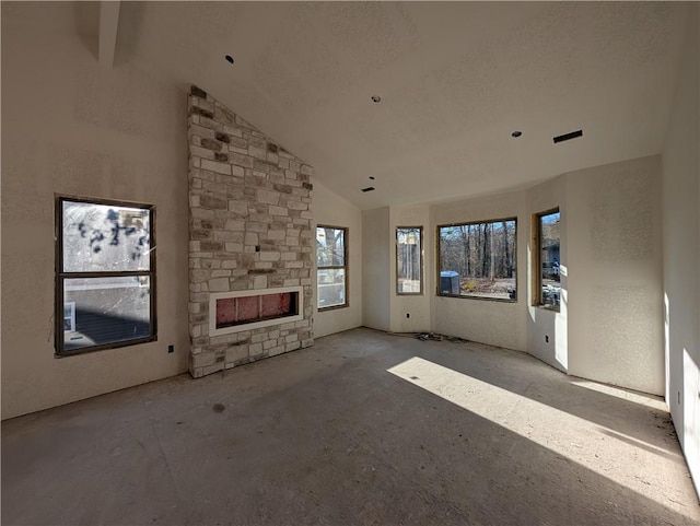 unfurnished living room featuring high vaulted ceiling and a stone fireplace