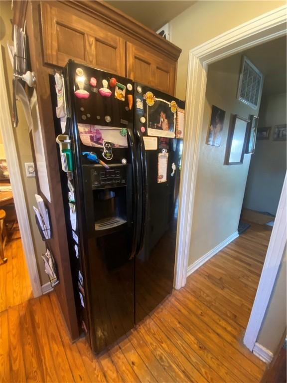 1312 S 9th St, Rogers, AR 72756 - kitchen with black refrigerator with ice dispenser, wood finished floors, brown cabinetry, and baseboards