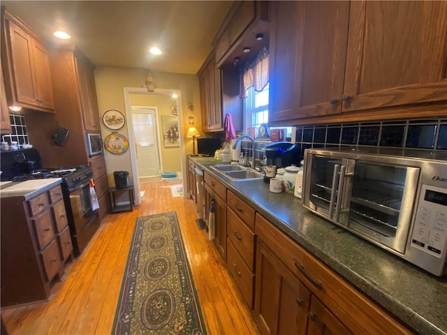 1312 S 9th St, Rogers, AR 72756 - kitchen with black gas range oven, a sink, tasteful backsplash, light wood finished floors, and dark countertops