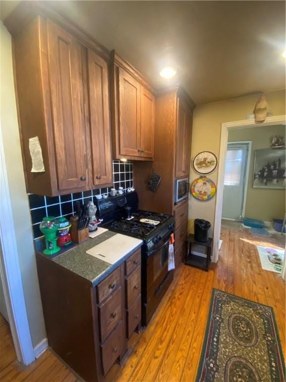 1312 S 9th St, Rogers, AR 72756 - kitchen featuring gas stove, light wood finished floors, decorative backsplash, stainless steel microwave, and brown cabinets
