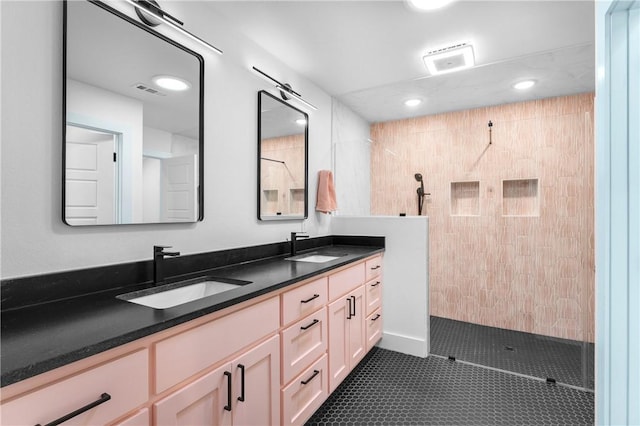 bathroom with tiled shower, vanity, and tile patterned flooring