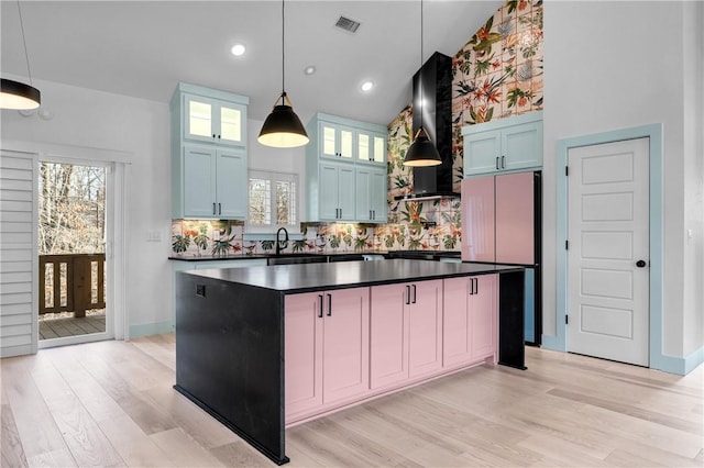 kitchen with a center island, pendant lighting, backsplash, and wall chimney exhaust hood