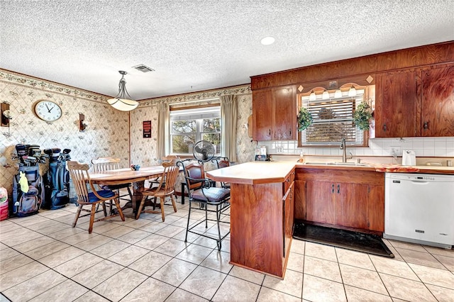 kitchen featuring sink, a breakfast bar area, kitchen peninsula, dishwasher, and pendant lighting