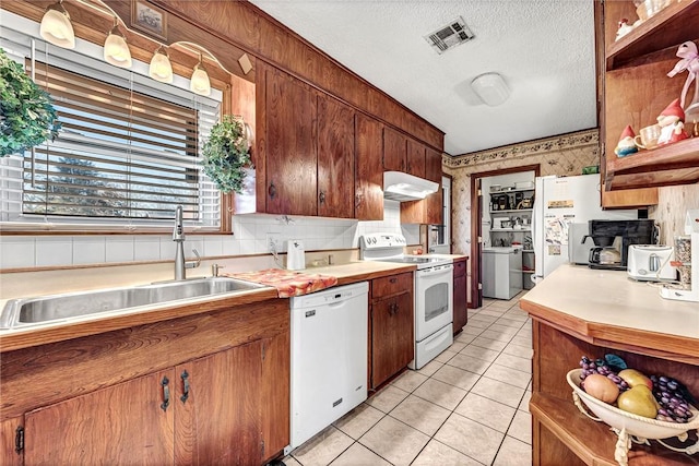 kitchen with light tile patterned flooring, sink, backsplash, white appliances, and a textured ceiling