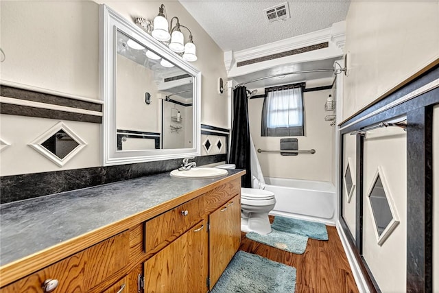 full bathroom featuring shower / tub combo with curtain, toilet, a textured ceiling, vanity, and hardwood / wood-style flooring