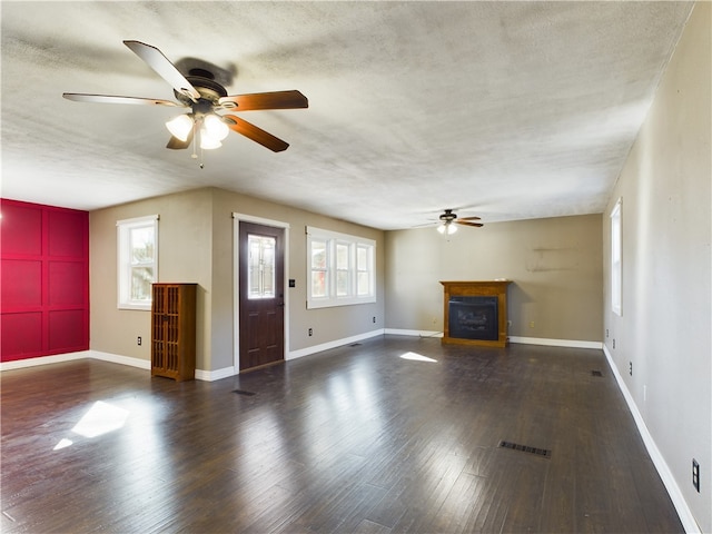 unfurnished living room with ceiling fan, a healthy amount of sunlight, and dark hardwood / wood-style flooring