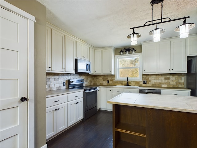 kitchen with sink, tasteful backsplash, hanging light fixtures, dark hardwood / wood-style floors, and black appliances