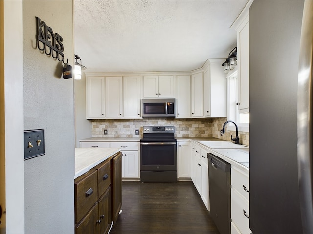 kitchen with appliances with stainless steel finishes, white cabinetry, sink, dark hardwood / wood-style flooring, and light stone countertops