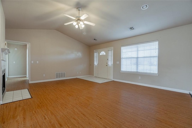 unfurnished living room featuring a fireplace, light hardwood / wood-style floors, ceiling fan, and vaulted ceiling