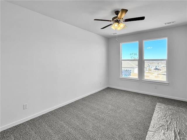 spare room featuring a ceiling fan, baseboards, visible vents, and dark carpet