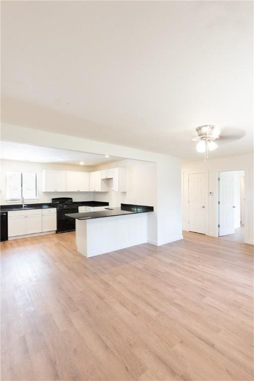 kitchen with sink, kitchen peninsula, white cabinets, light hardwood / wood-style floors, and black appliances