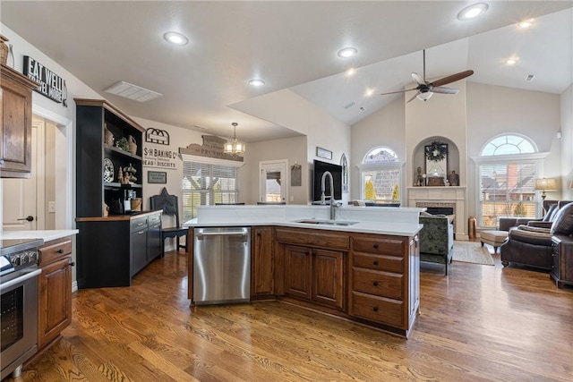 kitchen featuring dishwasher, an island with sink, sink, stove, and dark wood-type flooring