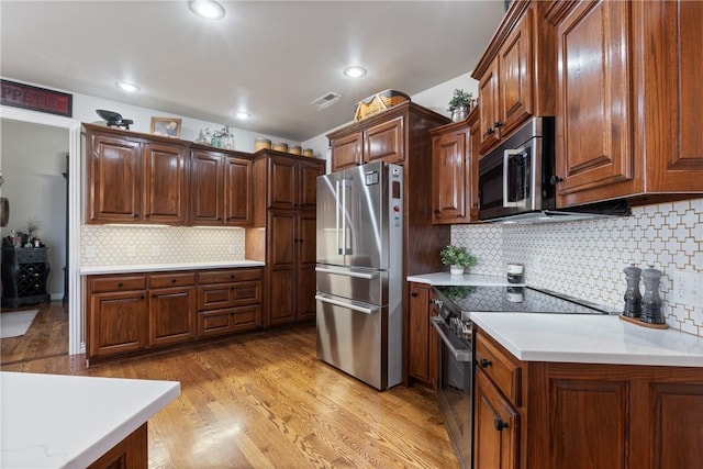 kitchen featuring appliances with stainless steel finishes, light hardwood / wood-style floors, and decorative backsplash