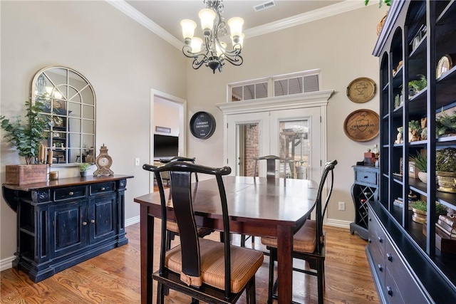 dining area featuring an inviting chandelier, ornamental molding, french doors, and light wood-type flooring