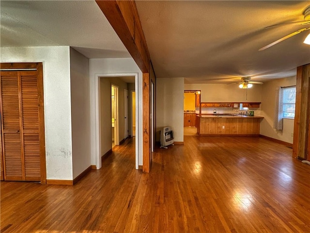 unfurnished living room featuring heating unit, dark hardwood / wood-style flooring, and ceiling fan