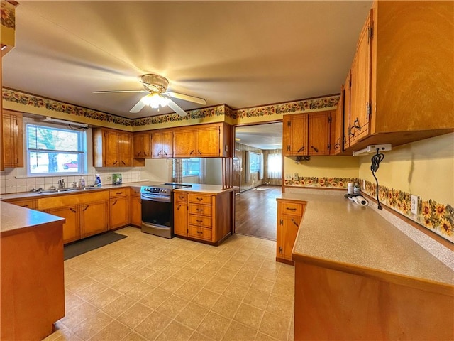 kitchen with sink, stainless steel electric range, a wealth of natural light, and kitchen peninsula