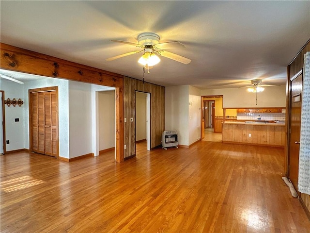 unfurnished living room with ceiling fan, light hardwood / wood-style floors, and heating unit