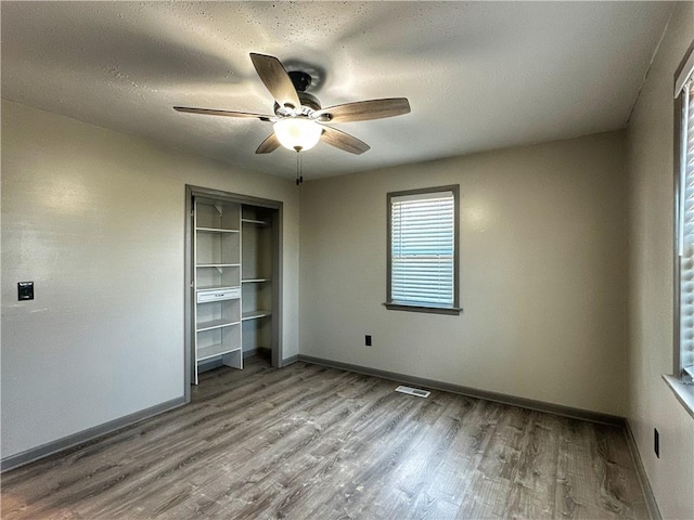 unfurnished bedroom featuring ceiling fan, a closet, light hardwood / wood-style flooring, and a textured ceiling