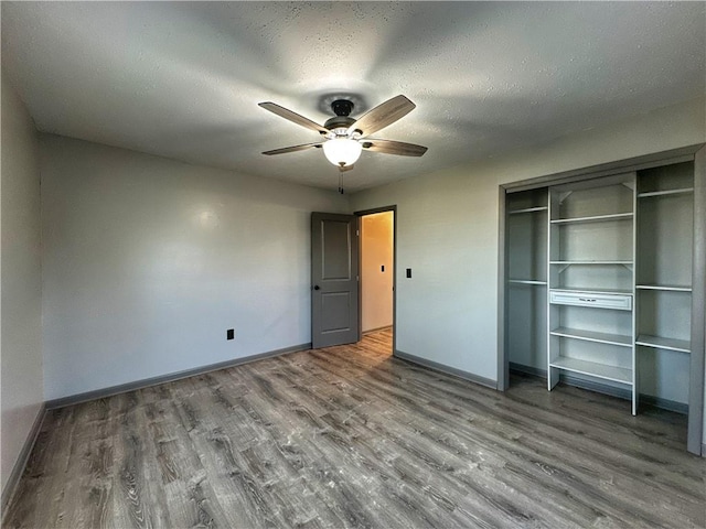 unfurnished bedroom with wood-type flooring, a textured ceiling, ceiling fan, and a closet