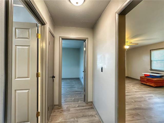 corridor featuring a textured ceiling and light hardwood / wood-style floors