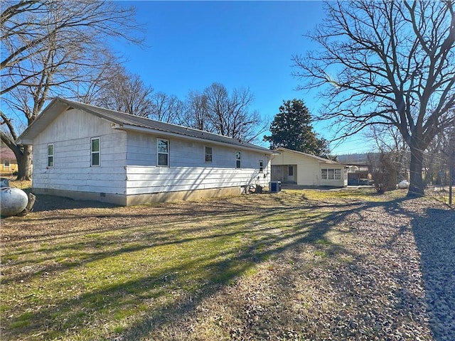 rear view of house with central AC unit and a yard