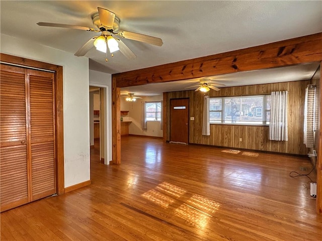 unfurnished living room with hardwood / wood-style flooring and wooden walls