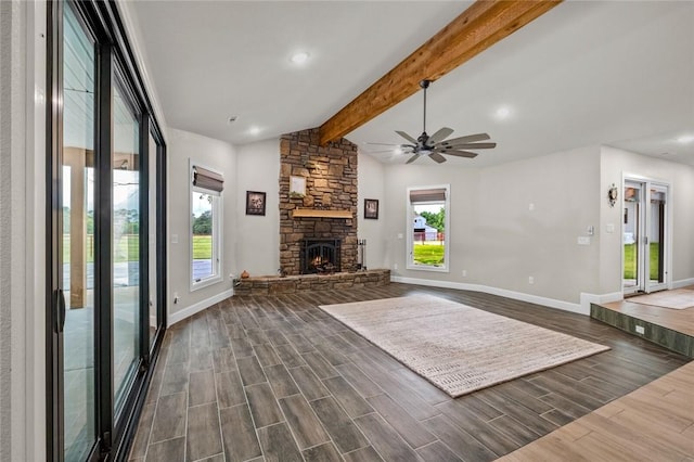 unfurnished living room with ceiling fan, a stone fireplace, and vaulted ceiling with beams