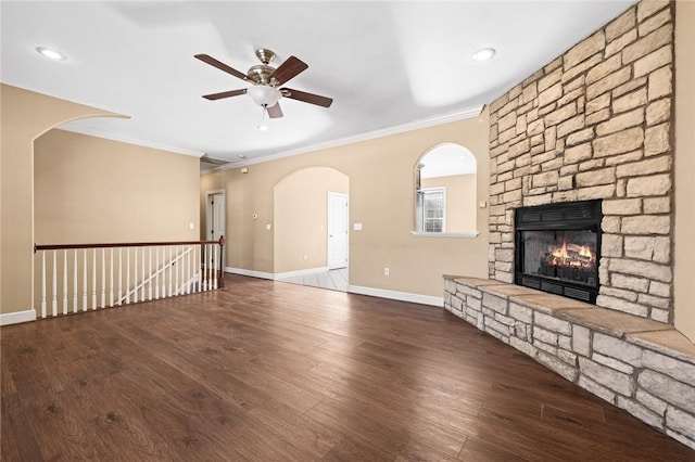 unfurnished living room featuring ornamental molding, a stone fireplace, wood-type flooring, and ceiling fan