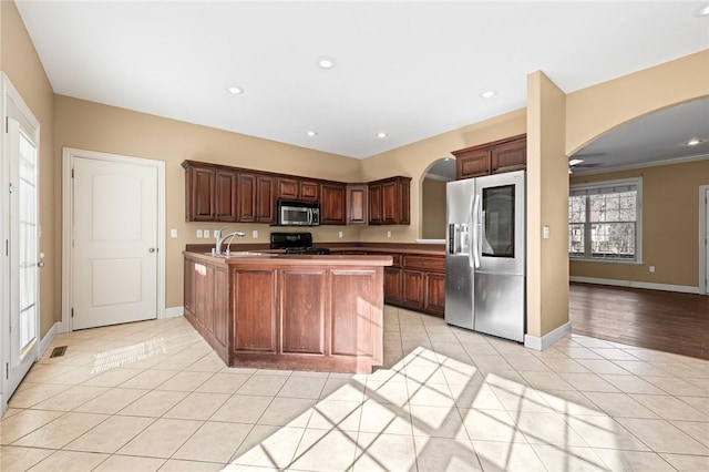 kitchen with appliances with stainless steel finishes, an island with sink, sink, light tile patterned floors, and dark brown cabinets