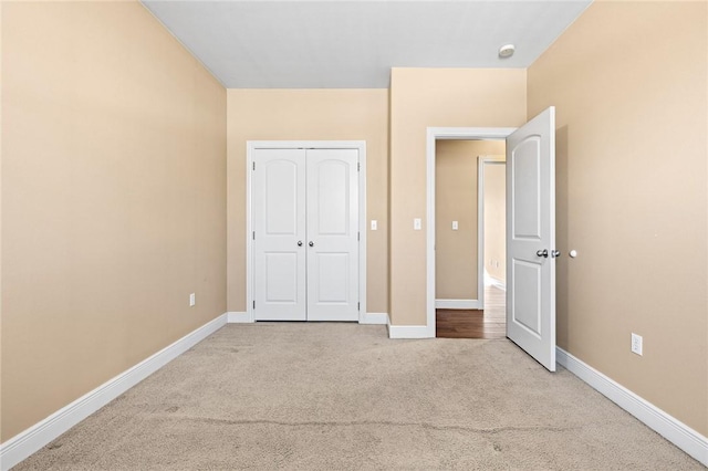 unfurnished bedroom featuring light colored carpet and a closet